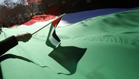 Manifestantes sostienen una bandera palestina gigante. Foto: EFE.