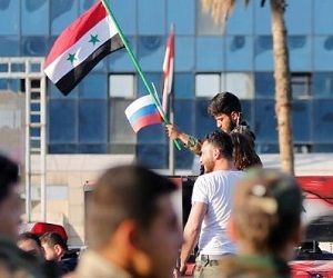 Joven sirio sostiene las banderas de su país y Rusia. Foto: EFE