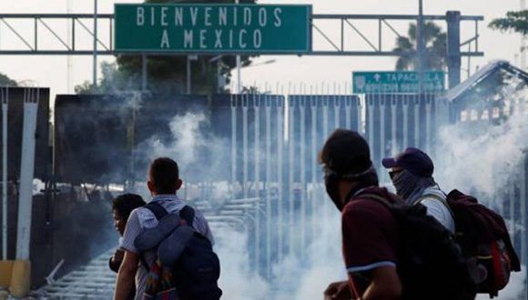 La caravana de migrantes rompe la valla que separa Guatemala de México. Foto: Reuters.