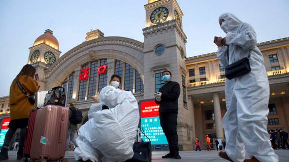 Pasajeros con trajes de protección contra la propagación del coronavirus esperan en el exterior de la estación de tren Hankou antes de la reanudación del servicio, en Wuhan, en la provincia de Hubei. Foto: AP.