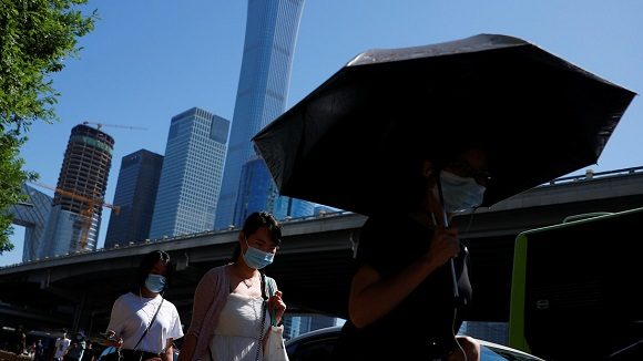 Personas con mascarillas en una calle del distrito comercial central de Pekín, China. Foto:Thomas Peter / Reuters.