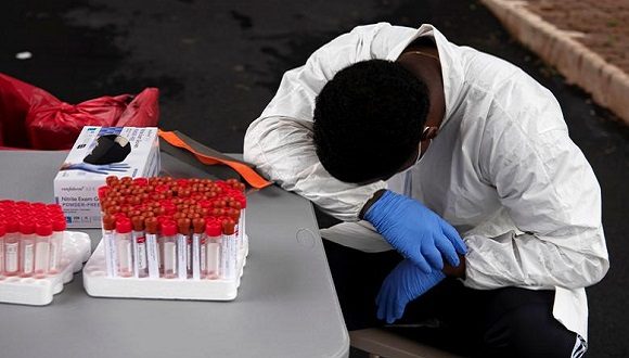 Un trabajador de la salud toma un descanso mientras la gente espera en sus vehículos en largas filas para la prueba de coronavirus en Houston, Texas. // Foto Callaghan O’Hare / Reuters