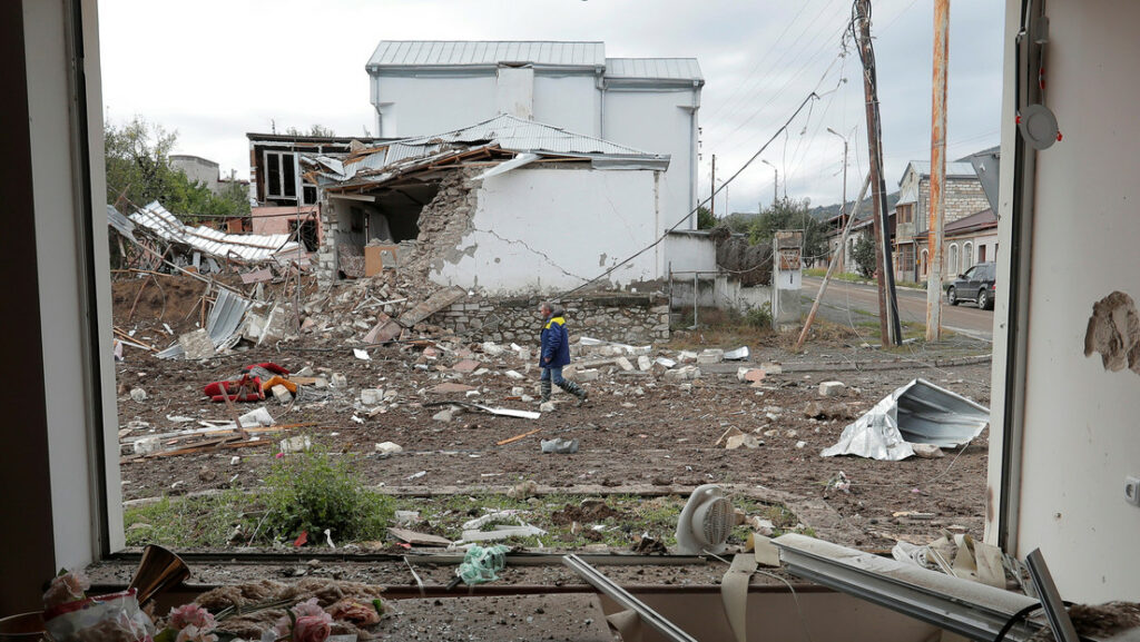 Un hombre pasa junto a una casa dañada por los bombardeos durante el conflicto militar en Nagorno-Karabaj, 8 de octubre de 2020.Reuters