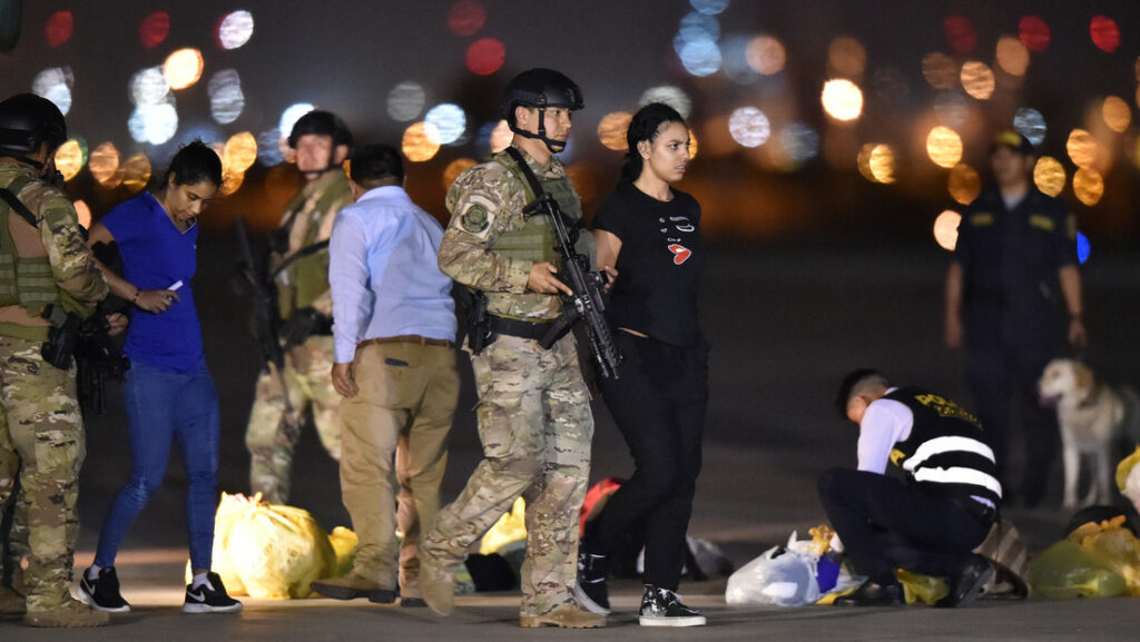 Un policía escolta a una mujer mientras un grupo de venezolanos es deportado en el Aeropuerto Internacional Jorge Chávez, en Lima, el 27 de enero de 2020Luka Gonzalez / AFP