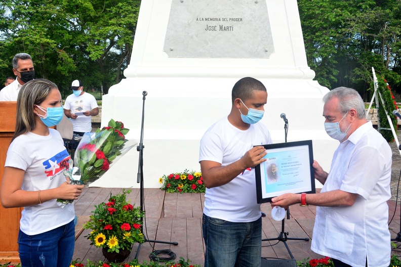 El Maestro de Juventudes, Wilfredo (Pachi) Naranjo Verdecia (D), director de la orquesta Original de Manzanillo, recibe el Premio Joven Patria, de manos de Dilberto González García (C), primer secretario de la Unión de Jóvenes Comunistas en Granma, y Yoanis Gallardo Vázquez (I), presidenta provincial del Movimiento Juvenil Martiano, en la conmemoración de la caída en combate de José Martí, el Apóstol de la independencia cubana, efectuada con motivo del aniversario 126 de ese suceso, en Dos Ríos, municipio Jiguaní, provincia Granma, Cuba, 19 de mayo de 2021. FOTO/ACN Armando Ernesto CONTRERAS TAMAYO/mvh