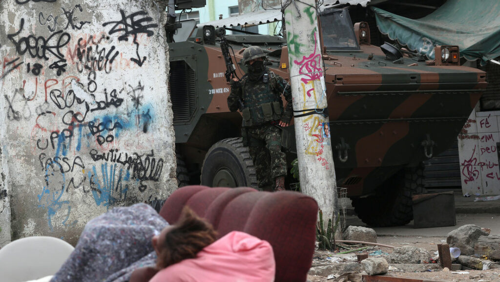 Una persona duerme en la calle, mientras militares patrullan una favela en Río de Janeiro.Ricardo Moraes / Reuters
