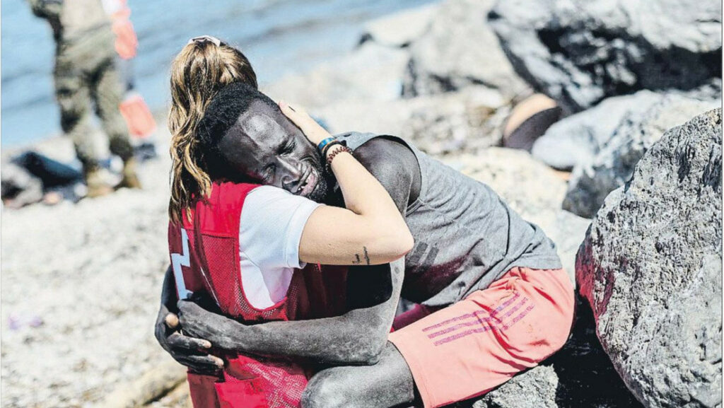 Luna, de 20 años, consolando a un migrante tras cruzar la frontera entre Marruecos y España en Ceuta, 19 de mayo de 2021.Twitter @CruzRojaEsp