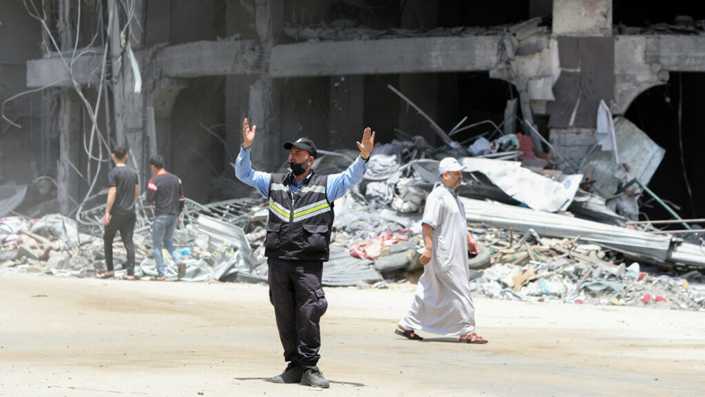 Un policía palestino dirige el tráfico cerca de un edificio dañado en la ciudad de Gaza el 21 de mayo de 2021.Mohammed Salem / Reuters
