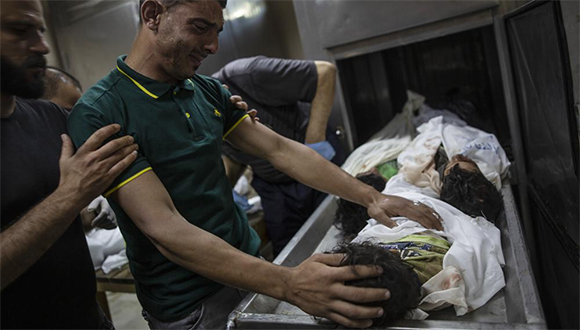 Un palestino llora sobre los cuerpos de cuatro niños de una misma familia, hallados bajo los escombros de una casa destruida tras ataques aéreos israelíes en Beit Lahiya, en el norte de la Franja de Gaza, viernes 14 de mayo de 2021. Foto: AP.