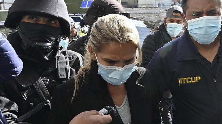 Former interim Bolivia’s President Jeanine Anez (C) is escorted by police members of the Special Force against Crime (FELCC) after being arrested in La Paz, on March 13, 2021. – Bolivia’s former interim president Jeanine Anez was arrested Saturday on terrorism and sedition charges over what the government claims was a coup attempt against her predecessor and political rival Evo Morales. (Photo by AIZAR RALDES / AFP)