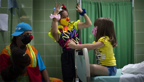 Una niña es entretenida por payasos mientras espera después de recibir una dosis de la vacuna Soberana 02 en La Habana, Cuba, agosto de 2021 // Foto: AP/ Ramon Espinosa