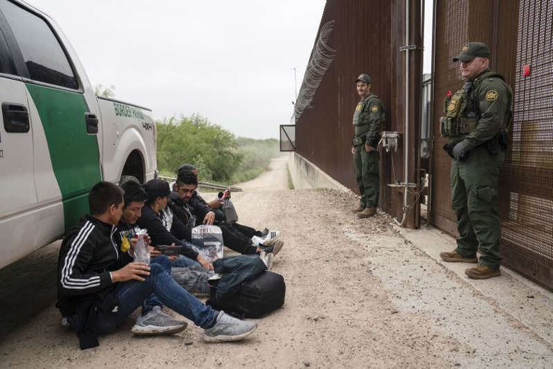 Migrantes colombianos que trataban de cruzar a Estados Unidos sin autorización legal esperan ser procesados por agentes de la Patrulla Fronteriza estadounidense el jueves 4 de mayo de 2023, cerca del cruce fronterizo en Hidalgo. // Foto: AP