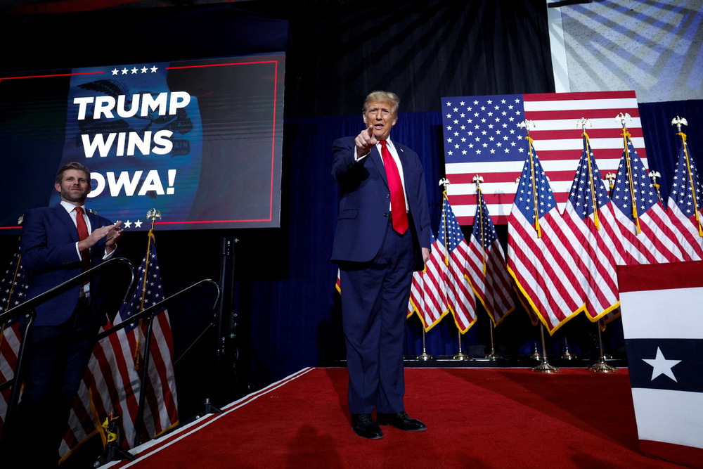 Republican presidential candidate and former U.S. President Donald Trump gestures as his son Eric Trump applauds next to him during his Iowa caucus night watch party in Des Moines, Iowa, U.S., January 15, 2024. REUTERS/Evelyn Hockstein