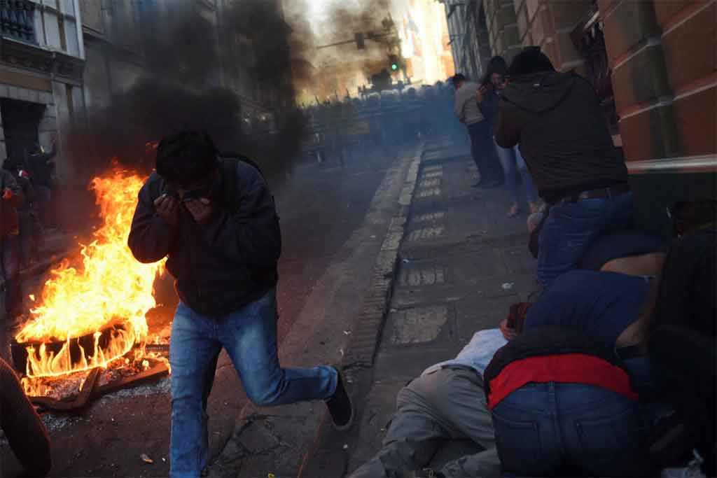 La gente se cubre la cara mientras los manifestantes se enfrentan a miembros del ejército de Bolivia, mientras el presidente de Bolivia, Luis Arce, «denunció la movilización irregular» de algunas unidades del ejército del país, en La Paz, Bolivia, junio 26, 2024. REUTERS/Claudia Morales