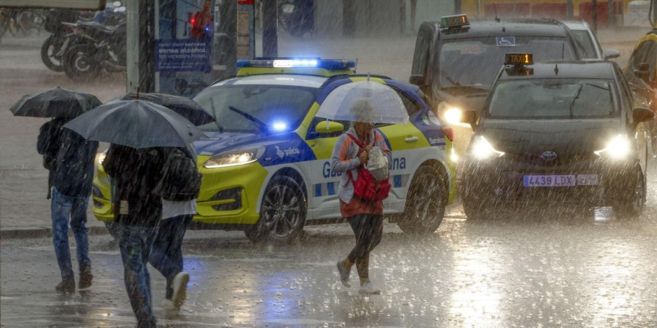 Varias personas se protegen de la lluvia en la Plaza de Espanya de Barcelona este lunes. Foto: Quique García/ EFE.