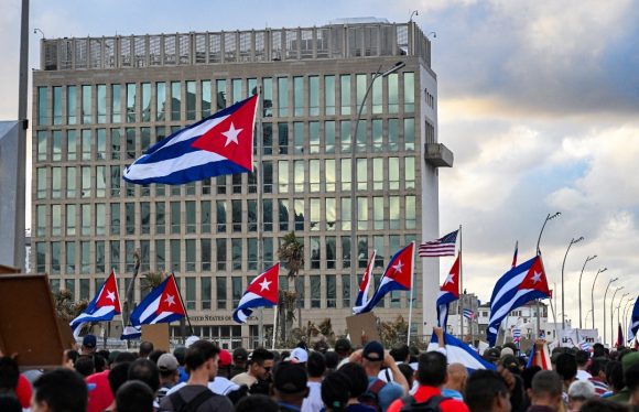 Los cubanos pasan frente a la embajada de Estados Unidos mientras marchan por el paseo marítimo de La Habana el 20 de diciembre de 2024, durante una manifestación contra el bloqueo y la permanencia de Cuba en la lista de países que patrocinan el terrorismo. (Yamil Lage / AFP vía Getty Images)