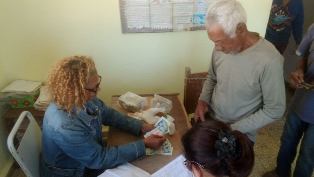 Trabajadora de Correo de Cuba Manzanillo, efectuando pago a jubilados de la zona de Los Letreros // Foto: Rafael González Castro.